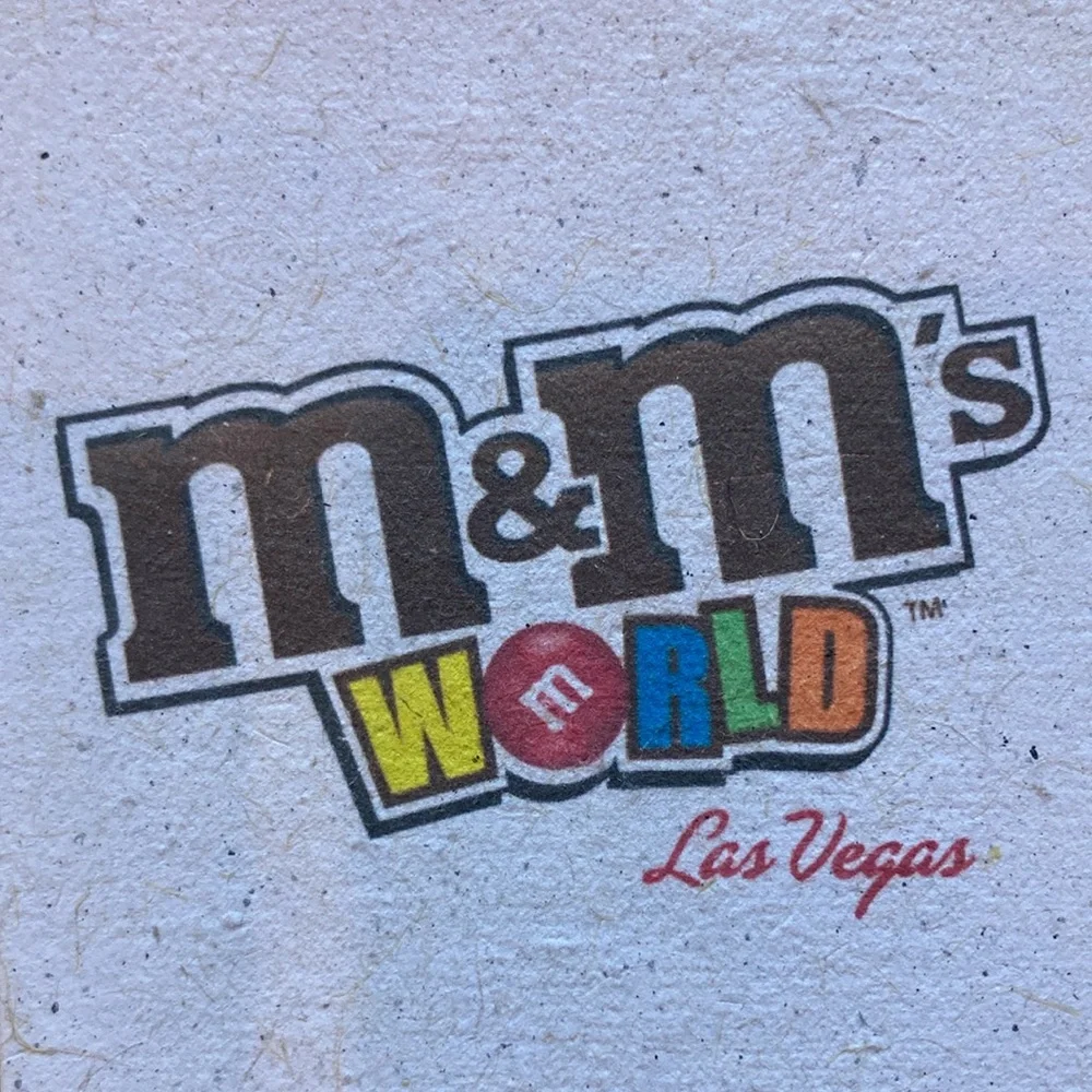 M&M'S World Logo Graphic with Red, Yellow, Blue, Green, Orange, Brown Accents